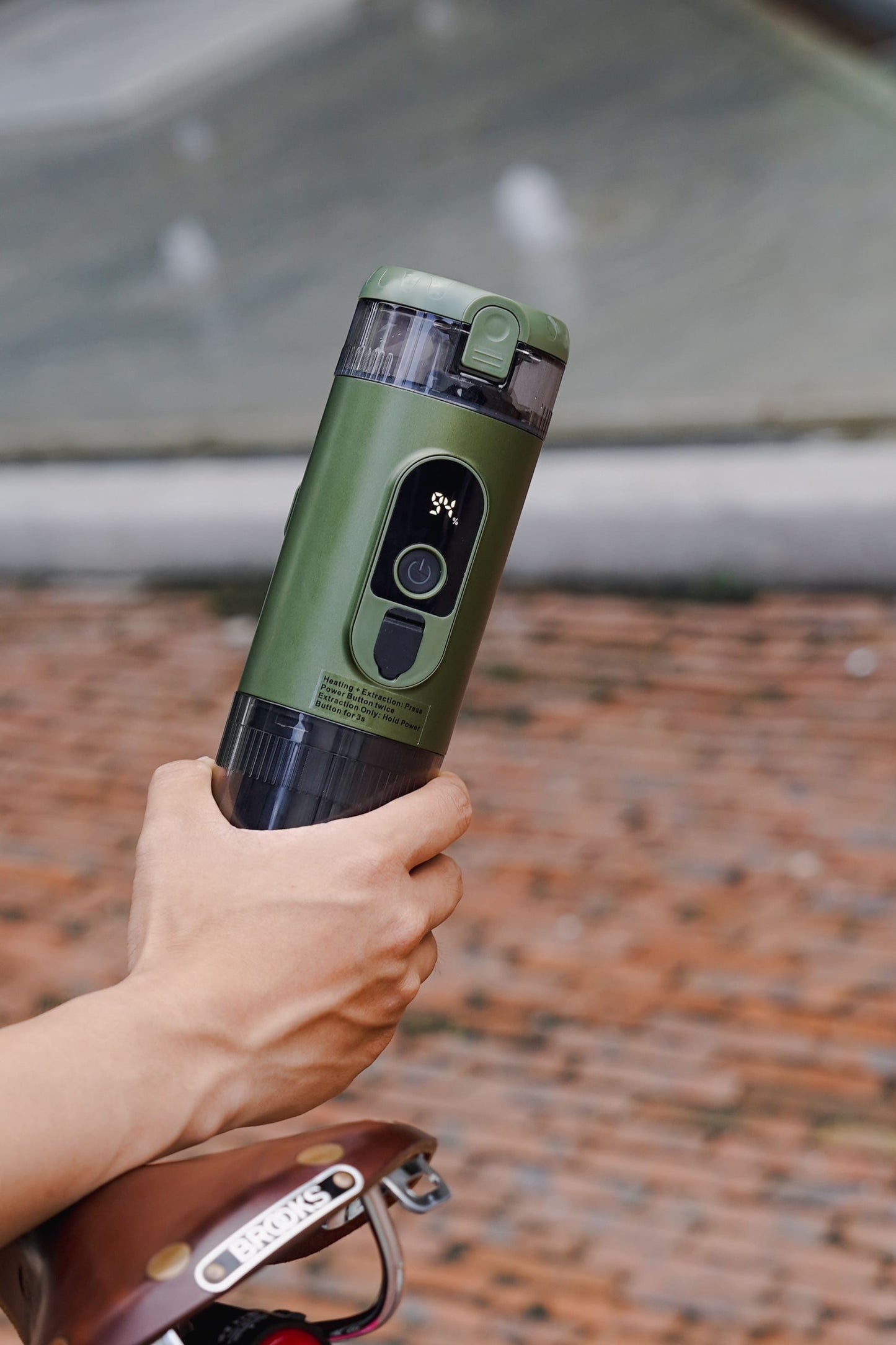 Hands holding TrailBrew green portable espresso maker outdoors