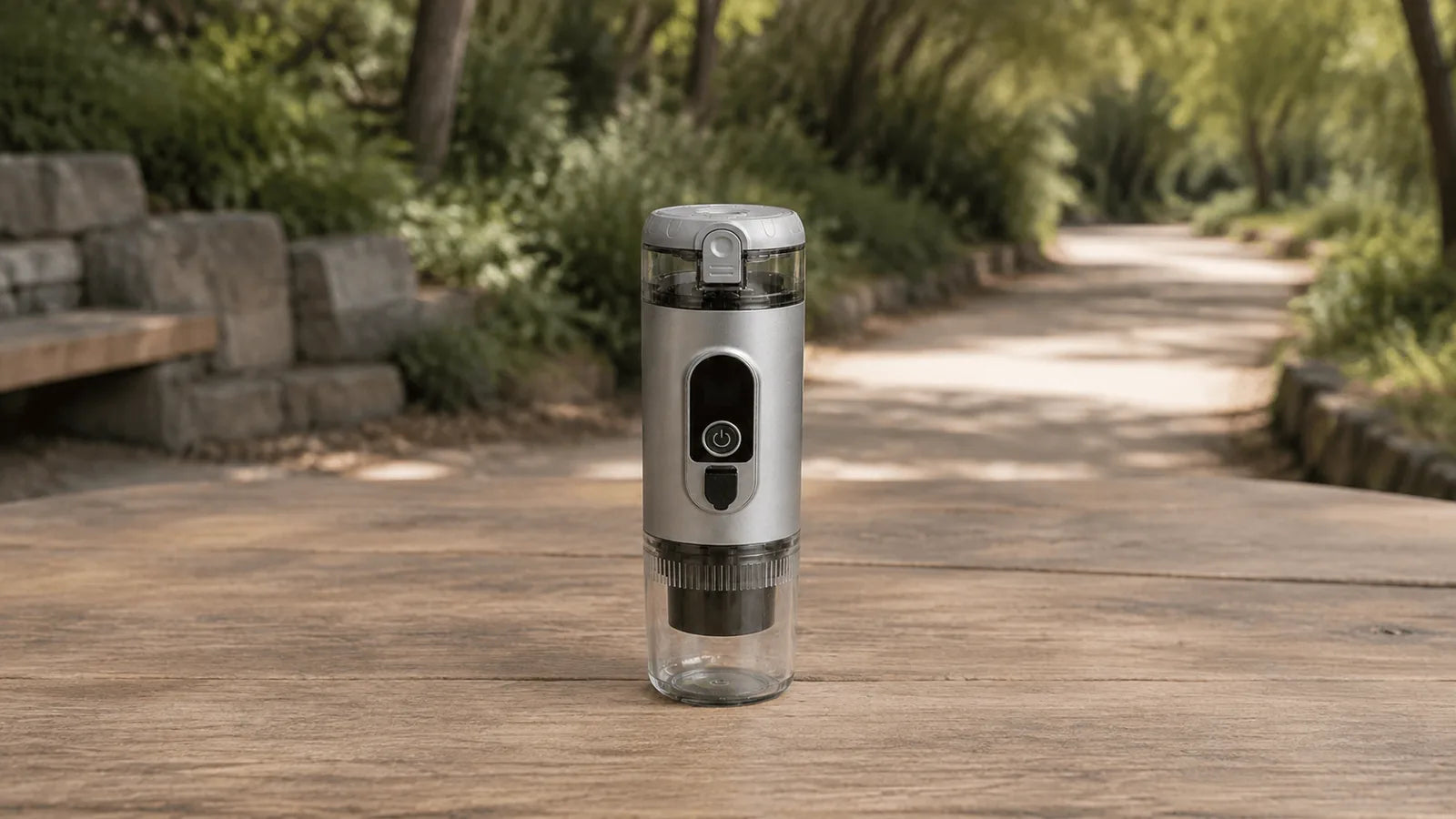 Closed Titanium Gray TrailBrew portable espresso maker on a dry shaded rest-area table beside a clear empty path.